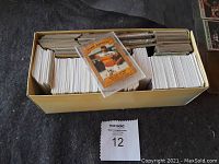 Wide view of the large box filled with assorted sports cards and a Nolan Ryan card on top.