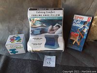 Photo of the entire lot including Calming Comfort Cooling Knee Pillow, mini vibrating body massager box, and SPRI exercise bands box.
