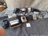 Photo showing all cameras and cassette recorder in the lot, arranged on a gray backdrop