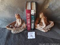 Full view of the two clay Native American bookends with two books placed in the middle, showing details of the handmade figures and Clay texture.