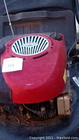 Close up of red Briggs and Stratton engine cover on lawn mower without grass catcher.