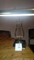 Vintage piano lamp showing illuminated horizontal light bar and brass lyre-shaped stand on marble base