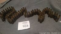 Photo of empty bullet casings arranged in snap-in clips forming a zigzag bandolier shape on a gray textured fabric.