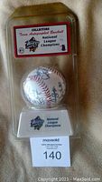Sealed original clear plastic packaging containing the autographed baseball and display stand with team logo and 1998 National League Champions label.