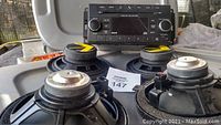 Photo showing Jeep Wrangler stereo head unit with four round speakers arranged in front of it on a surface.