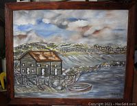 Front view of framed oil painting depicting coastal scene with houses and boat.