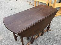 Photo of antique wooden gate leg drop leaf table with leaves folded down, showing rectangular shape and turned legs.
