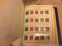 Open album page showing a selection of United States postage stamps mounted and labeled by denomination and type.