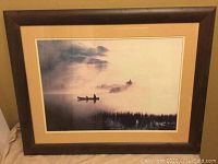 Full view of professionally framed art showing a person and dog canoeing in misty waters with wood frame and beige matting.