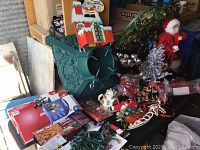 Photo of large variety of Christmas decorations including figurines, miniature houses, and decorative items on a black table surface.