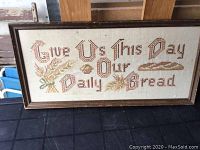 Full view of framed cross stitch with phrase and motifs on fabric.