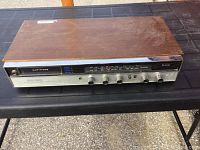 Front view of vintage 8 track player showing wooden top and metal front panel with control knobs and tuning dial.