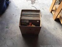 Single photo showing a cardboard box filled with approximately 50 vintage LP records, topmost record has Elvis Presley on cover.
