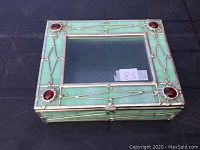Closed view of the rectangular stained glass jewelry or trinket box with green panels and red decorative glass accents at each corner of the lid.