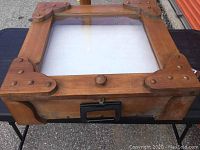 Top view of the wooden tabletop showcase showing glass top and decorative corner braces, wood finish, and round knob.