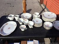 Full view of the 50-piece antique dish set, including plates, bowls, teacups, creamer, sugar bowl, and serving platter arranged on table.