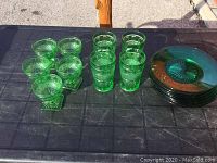 All lot items arranged on black table showing glasses, dessert dishes, and plates in green glass with textured patterns.