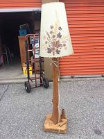 Full view of lamp showing wooden carved base and tall floral Dornbush shade with lamp cord visible.