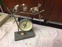Full view of the bird clock showing three metal birds perched on a metal branch above the clock face and rectangular base.