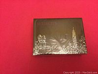 Photo of a sealed rectangular perfume box with "SEX AND CITY" branding and city skyline design.