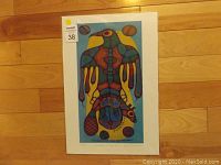 Full view of the Norval Morrisseau print in protective plastic sleeve with cardboard backing showing complete artwork and style.