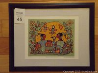 Full view of the framed fine art print showing the artwork with the large yellow sun, two stylized Indigenous figures, and floral elements, with visible auction lot number.