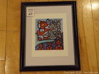 Framed colorful fine art print by Christian Morrisseau showing abstract figures and cherries, within a black frame with silver accents and white matting.