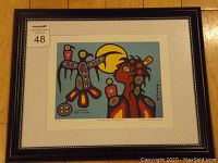 Framed Indigenous artwork print with visible artist signature, number and title under the image, framed black with silver bead detail.