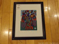 Framed artwork lying on wood floor, showing entire frame and artwork inside.