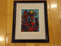 Full frontal image showing the framed art print on a wooden floor with auction tag 73.
