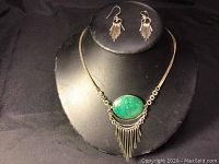 Front view of necklace with green jasper stone and matching earrings displayed on a black stand