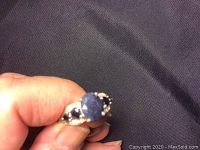 Close-up photo showing the front view of a sterling silver ring with a large round sapphire stone in the center and smaller sapphire stones on the sides