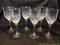 Front view of six crystal wine glasses arranged in two rows on a black background.