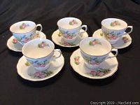Set of five Crown Royal cups and saucers arranged on a black surface showing the full set.