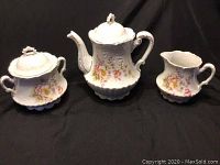 Full set of three vintage porcelain items: teapot, sugar container, and milk jug, all decorated with floral patterns and gold accents.