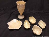 Six Belleek porcelain pieces displayed including one vase and five small nipping bowls of various leaf and shell shapes.