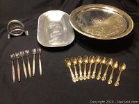 Full view of the lot showing the serving platter, pedestal cake stand, metal coasters with stand, gold plated dessert spoons and oyster forks.