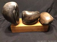 Front view showing three carved wood forms on rectangular base