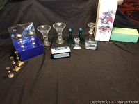 Full lot showing all brass candle holders, crystal candle holders, and boxed flower arrangers arranged on black cloth