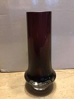 Front view of cranberry art glass vase with clear thick base, showing smooth surface and shape