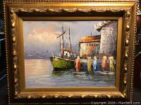 Framed oil painting showing the entire artwork with gold ornate frame and the harbor scene with boats and dock pilings.