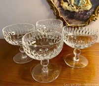 Four Waterford crystal liquor glasses arranged closely on a wood surface, showing clear cut crystal and pattern detail.