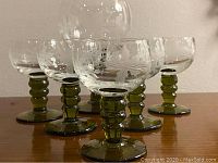 Set of six vintage etched wine glasses with green stems, one larger than the others