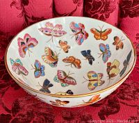 Top view showing the inside of the porcelain bowl filled with various multicolored butterflies hand painted with gold accents.