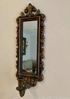 View of full wall sconce showing rectangular mirror with ornate carved frame and attached taper candle holder beneath.