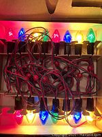 Vintage 15 light NOMA Christmas lights lit with multicolor bulbs, tangled wire visible.
