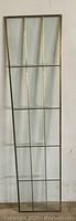Front view of one brass and beveled glass panel showing rectangular sections divided by brass bars, tall and narrow shape.