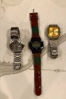 Three watches laid out on marble surface showing full watches and bands.