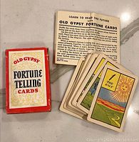 Photo showing box, instruction sheet, and a spread of fortune telling cards displaying one card face showing 'The Sun'