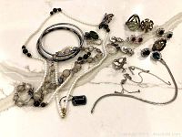 Overview photo showing all pieces including bracelets, necklaces, earrings and brooches arranged on light marble surface.